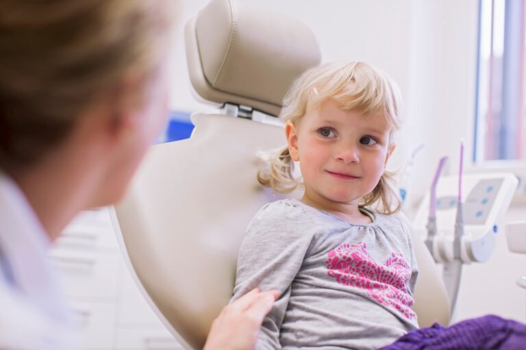 Worried looking girl in dentist chair chatting with dentist
